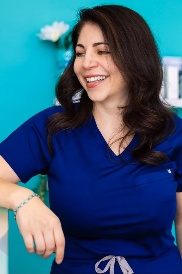 Anita Samadian, owner of Sunwaves Facial Studio, smiling at the studio's front desk.